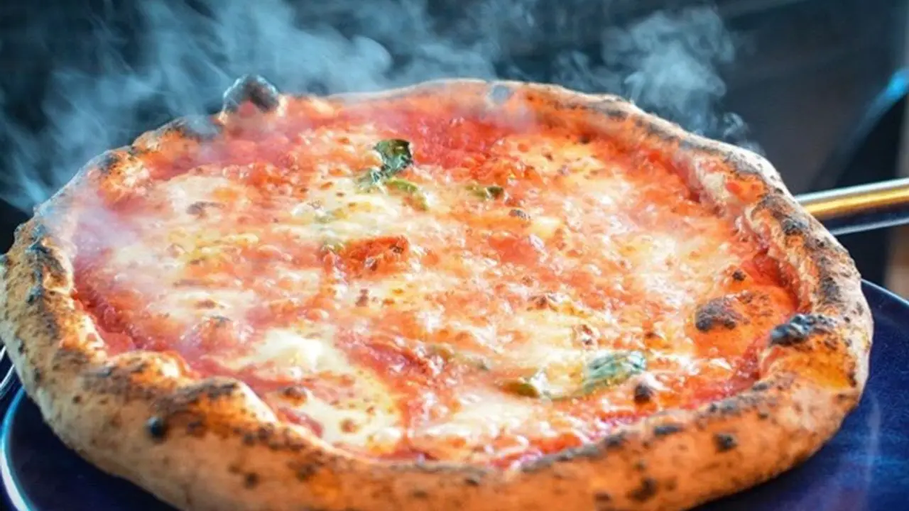 Pizza napolitana recién horneada con tomate, mozzarella y albahaca en Brunapoli