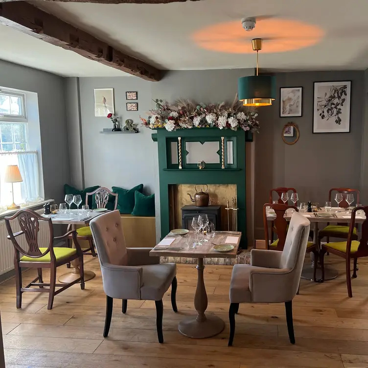 Tables surrounding green fireplace with flowers on - Pear & Olive, Hildersham, England