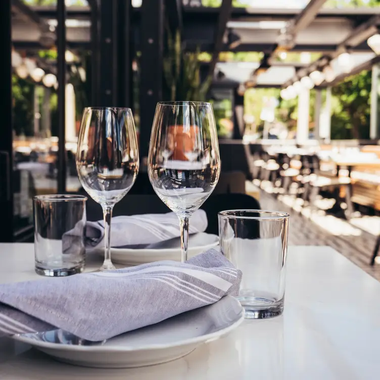 Summer on the patio with wine glasses and plates - Osteria Rialto, Toronto, ON