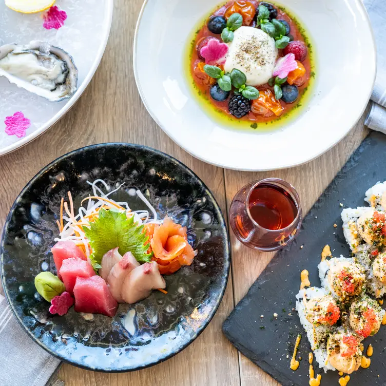 Table of food -sushi, oysters, sashimi, burrata - WOVEN Seafood & Chophouse by Roy Yamaguchi, Tacoma, WA