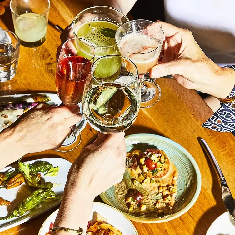 People cheering at a table with drinks and food - Wildseed CA San Francisco