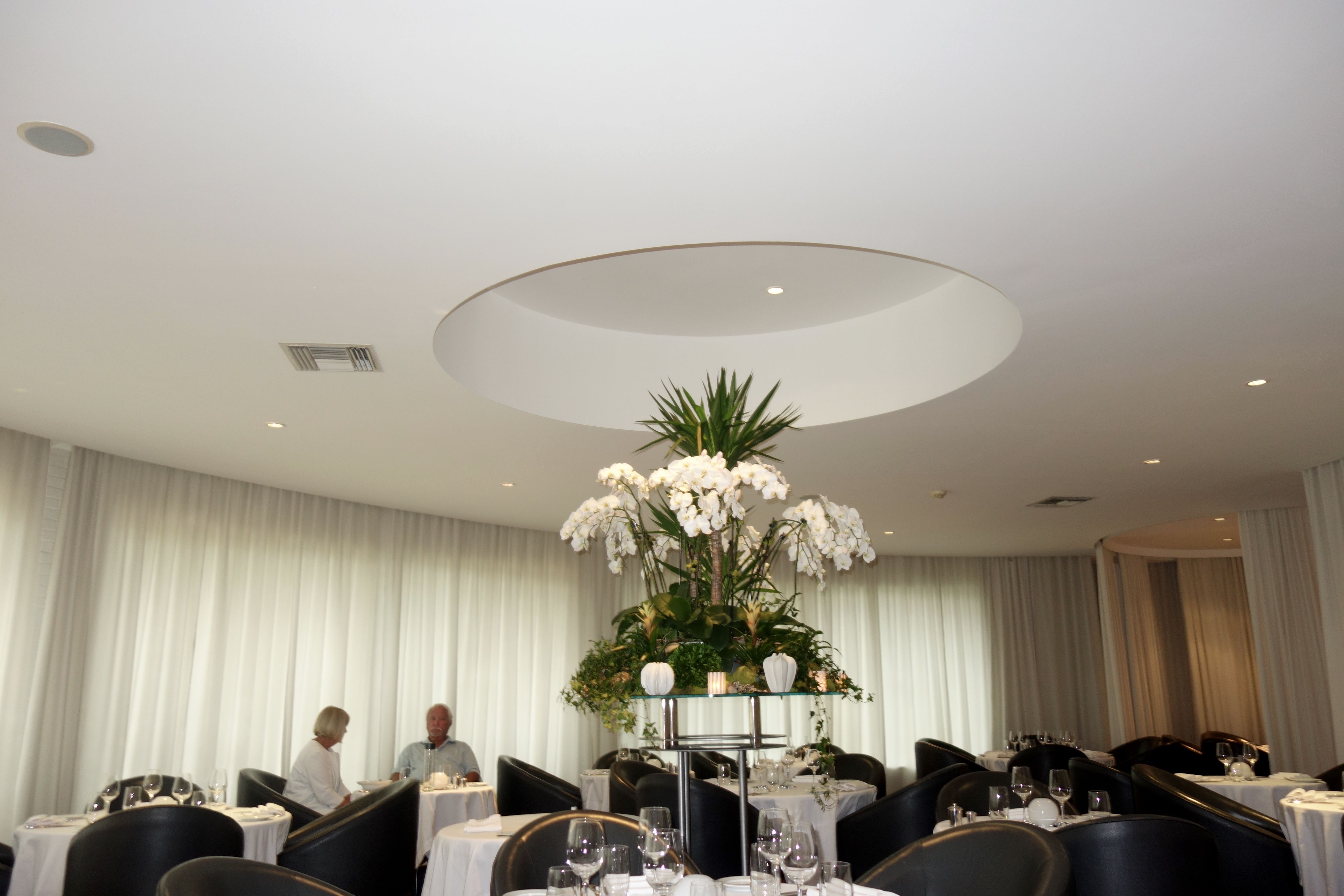Maison Blanche dining room on Longboat Key with white linens, orchids and contemporary seating.